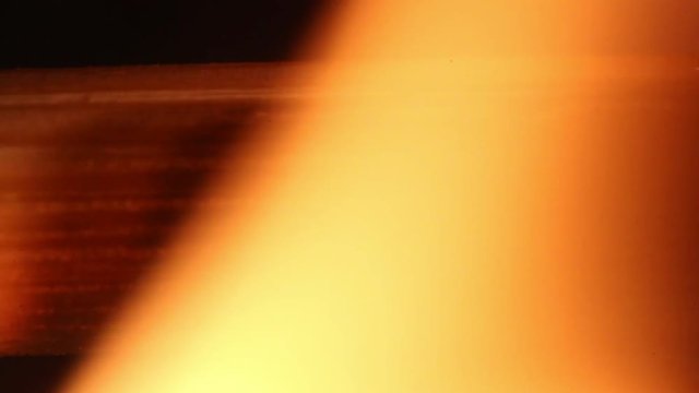 Flames burn through pice of wood, macro close up