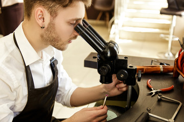 A jeweler carefully examines the stone to create a ring through a microscope