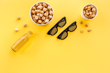Fototapeta na wymiar Snacks for film watching in the cinema. Popcorn and soda near glasses on yellow background top view copyspace