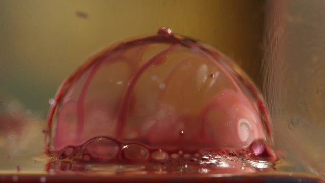 Single red bubble floats on water, close up