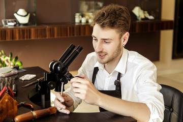 The jeweler examines the gem under the magnifying glass