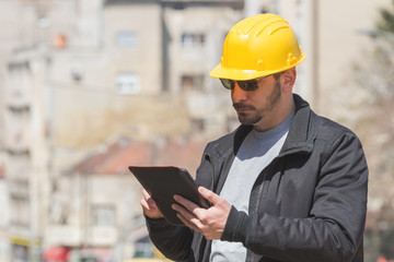 Real and ordinary construction worker using tablet on his job.