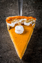 Traditional autumn dishes. Halloween, Thanksgiving. One piece of spicy pumpkin pie with whipped cream & pumpkin seeds on black stone table. Copy space