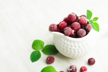 Frozen cranberry in white sauce pan with fresh mint