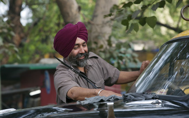 Sikh taxi driver cleaning his vehicle 