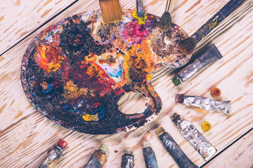 Oil paints and paint brushes on a palette close up.