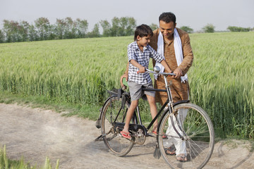Obraz premium Father teaching son how to ride cycle 
