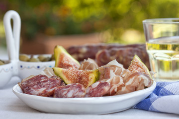 traditional mediterranian meat appetizers with olives, figs and white wine
