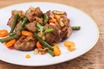 Sauteed liver with vegetables on white plate