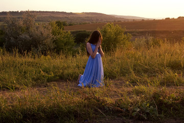 The girl bowed her head in prayer at sunset