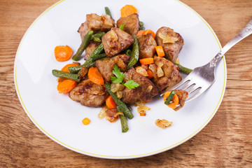 Sauteed liver with vegetables on white plate