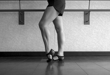 Black and white version of Jazz dance class, barre work foot in dig