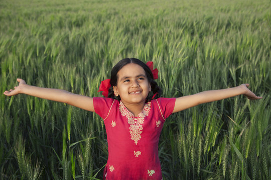 Little girl standing with arms out in a wheat field 