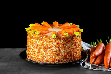 Plate with delicious carrot cake on black background
