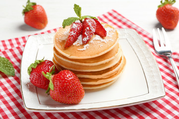 Plate with delicious pancakes on table