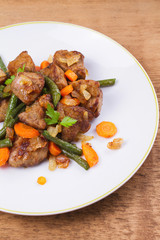 Sauteed liver with vegetables on white plate
