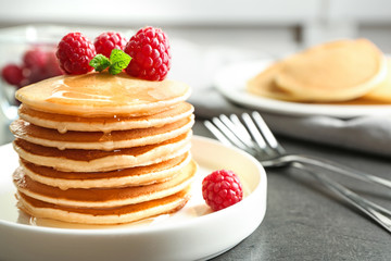 Plate with delicious pancakes on table
