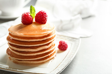 Plate with delicious pancakes on table