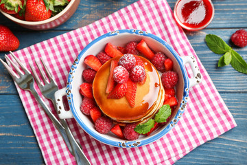 Casserole with delicious pancakes on table