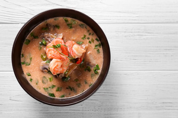 Delicious soup with shrimps in bowl on wooden background