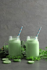 Mason jars with fresh smoothie and vegetables on table