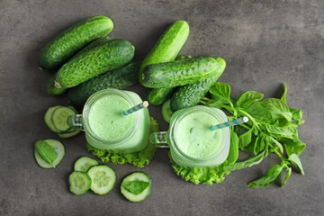 Mason jars with fresh smoothie and vegetables on grey background