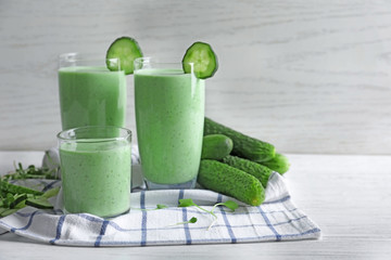 Glasses of fresh smoothie with cucumbers on table