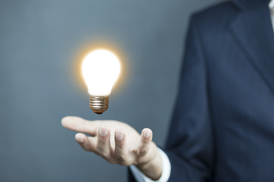 businessman holding a creative light bulb icon in his hands conceptual of ideas