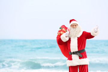 Authentic Santa Claus with big red bag full of gifts on sea background
