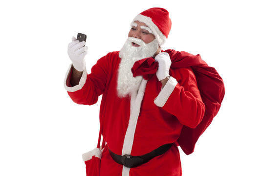 Front view of Santa Claus looking at mobile phone while carrying sack of Christmas presents 