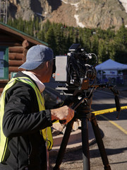 Camera Operator Shooting with Mountains in Background