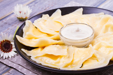 Varenyky, vareniki, pierogi, pyrohy or dumplings, filled with sweet cottage cheese (farmer cheese) and served with sour cream - traditional Ukrainian, Russian and Polish dish