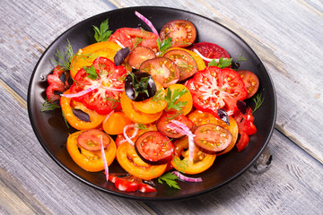 Different sorts of tomatoes, parsley, dill and red onion salad