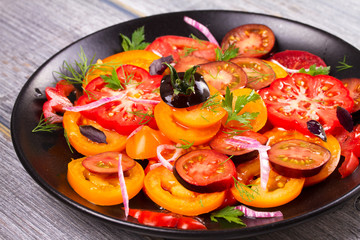 Different sorts of tomatoes, parsley, dill and red onion salad