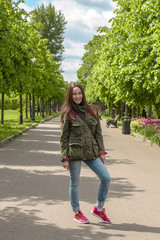 Happy young woman in sports clothing walking in summer Park