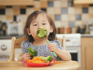baby girl eating  vegetable at home