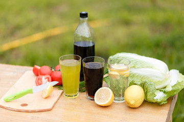 With a knife cut a lemon on a wooden Board background with fresh vegetables and summer lemonade and a wood Desk. Sliced lemons and a knife on a cutting Board.