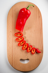 Partly sliced red hot chili pepper on a breadboard