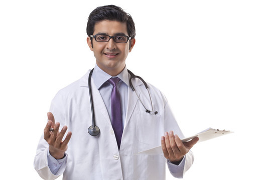 Handsome male doctor holding clipboard gesturing on white background 