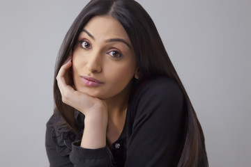 Fototapeta premium Portrait of a bored young woman with hand on chin isolated over colored background 