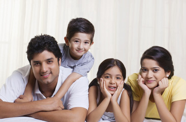 Portrait of happy family lying in bed 