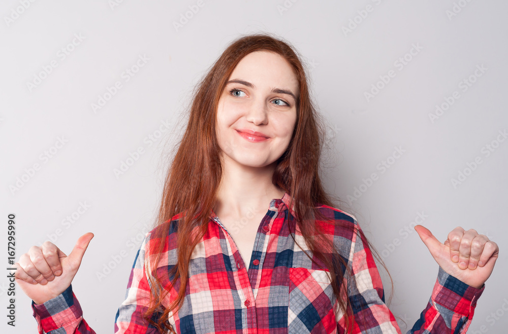 Wall mural happy young woman with long hair in red checkered shirt pointing at herself and smiles. the concept 