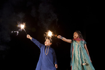 Fototapeta na wymiar Boy and girl playing with sparklers