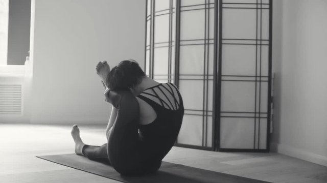 A young woman performing yoga-asanas in the hall.