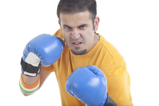 Portrait of an aggressive young man wearing boxing gloves over white background 