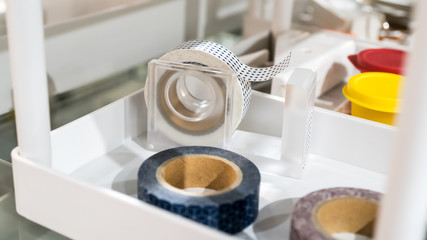 Rolls of masking tapes with cute patterns in dispenser stand on white shelf