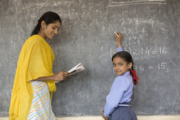 Rural student writes on the board as tea 