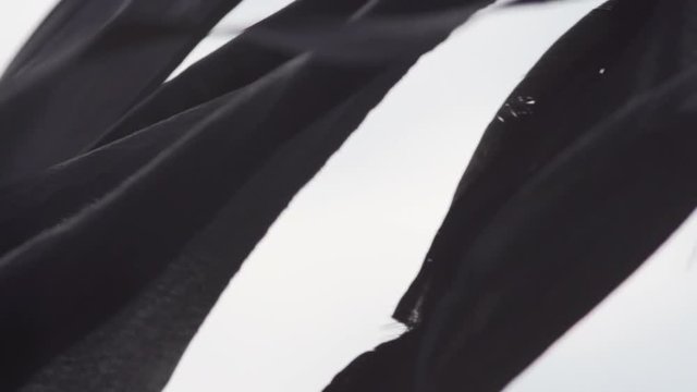 Black Strips of Fabric Blowing Against Sky