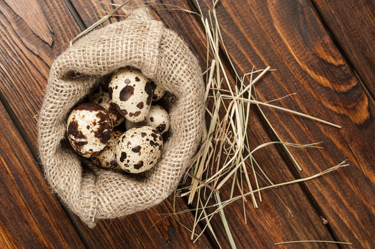 top view on quail eggs in burlap sack over old wooden background