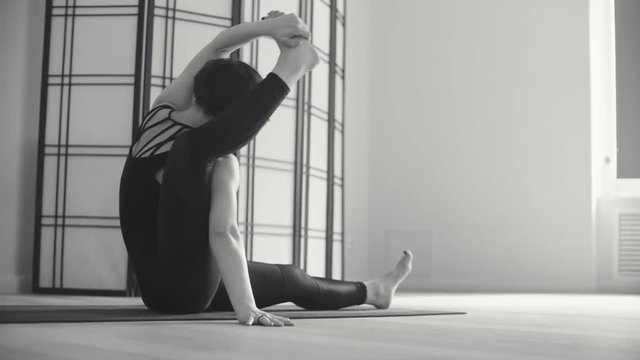 A young woman performing yoga-asanas in the hall.